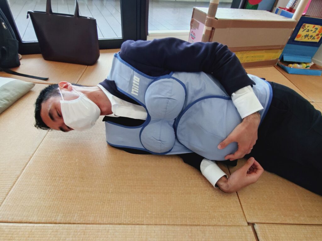 妊婦体験ジャケット着用中（寝転がるさかす編集長）