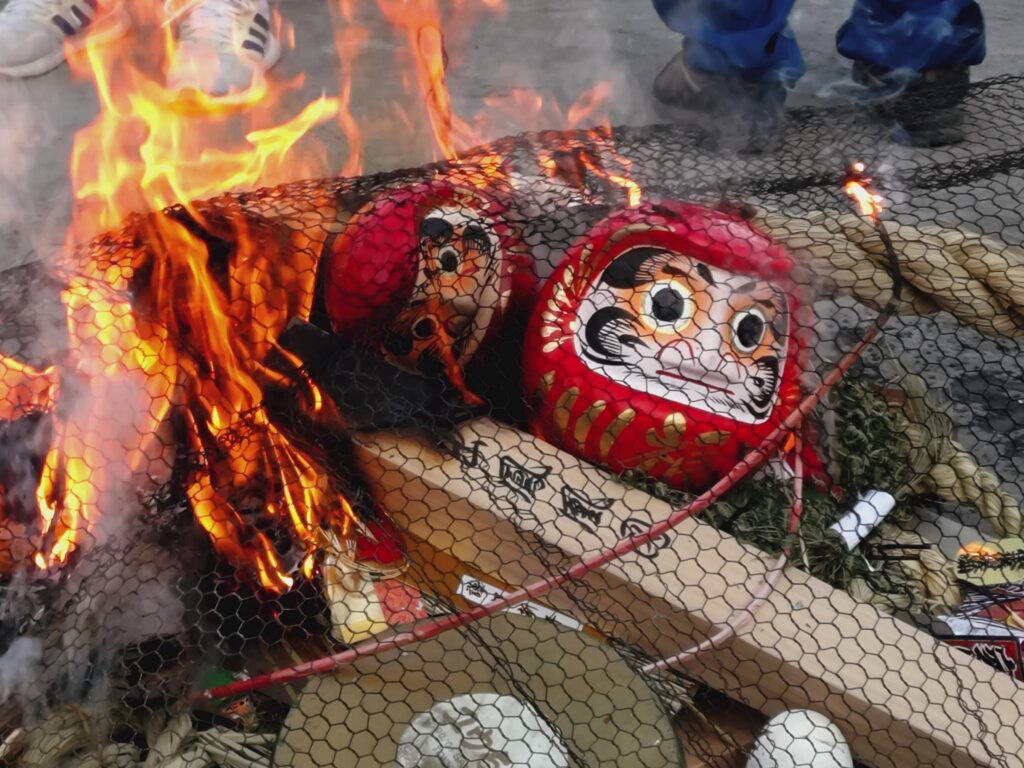 どんど焼きの火にくべられるダルマ