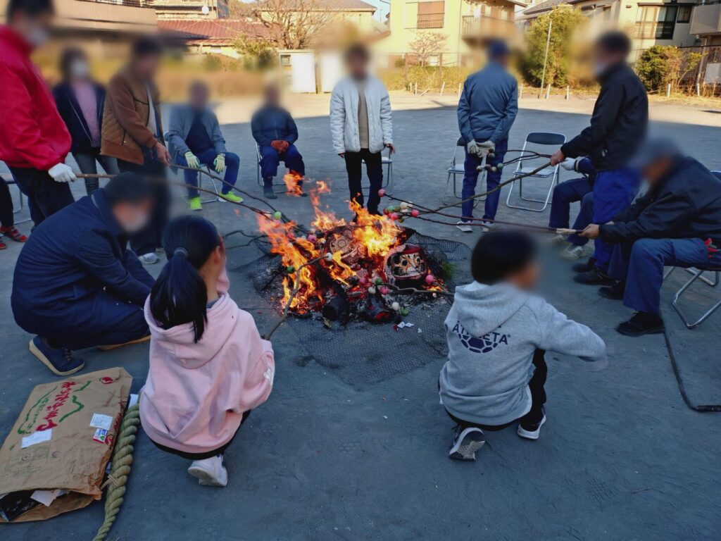 焚き火を囲んで団子を焼く人々