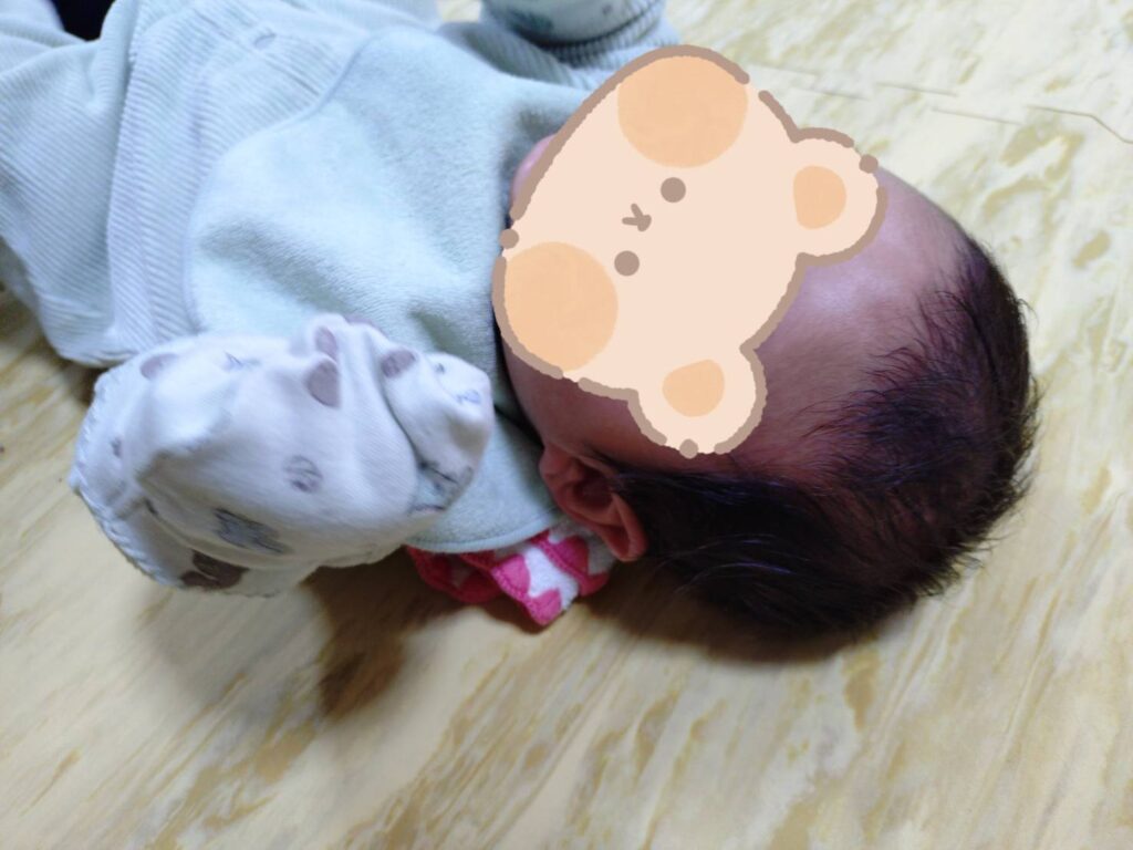 ハンカチを丸めた「首枕」を赤ちゃんの首の下に置いています。