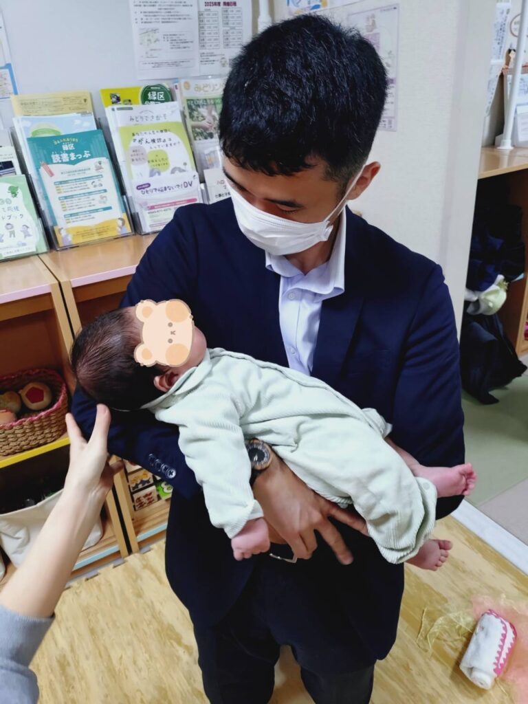 加藤先生に抱っこのやり方のレクチャーを受けている、さかす編集長