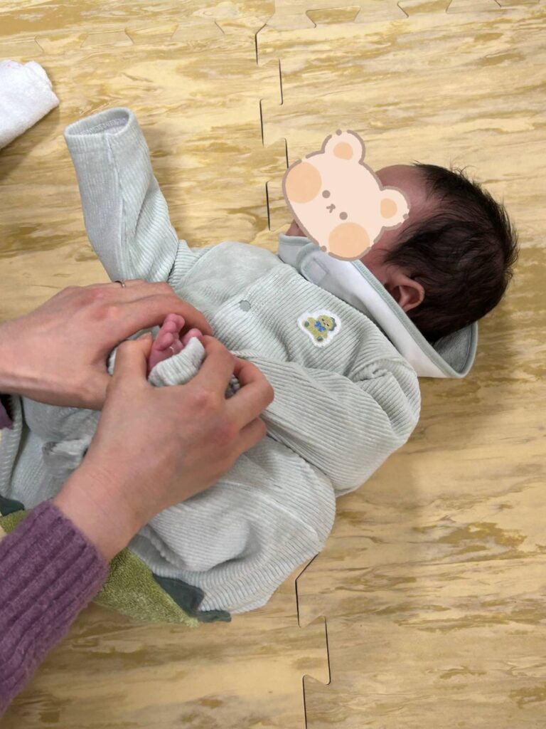 赤ちゃんの足と腕を掴んで、ダンゴムシのような姿勢を作る