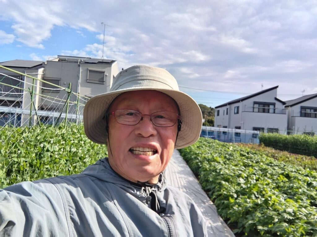 自慢の畑と共に写る日出山さん