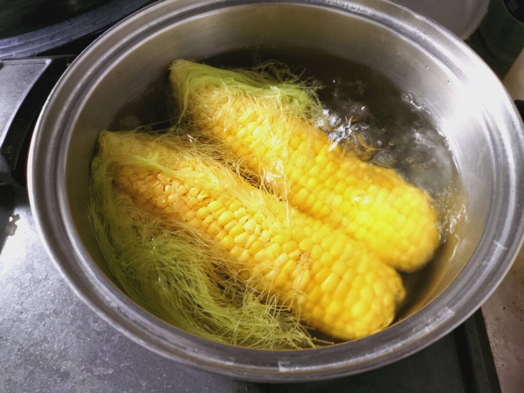 沸騰したお湯でトウモロコシ2本を湯がいている様子